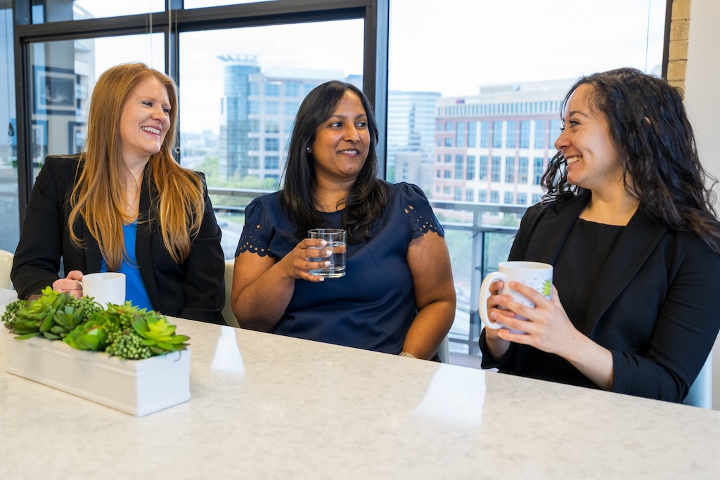 Thomas Edwards Group employees woman in pink shirt writing as co workers talk in background